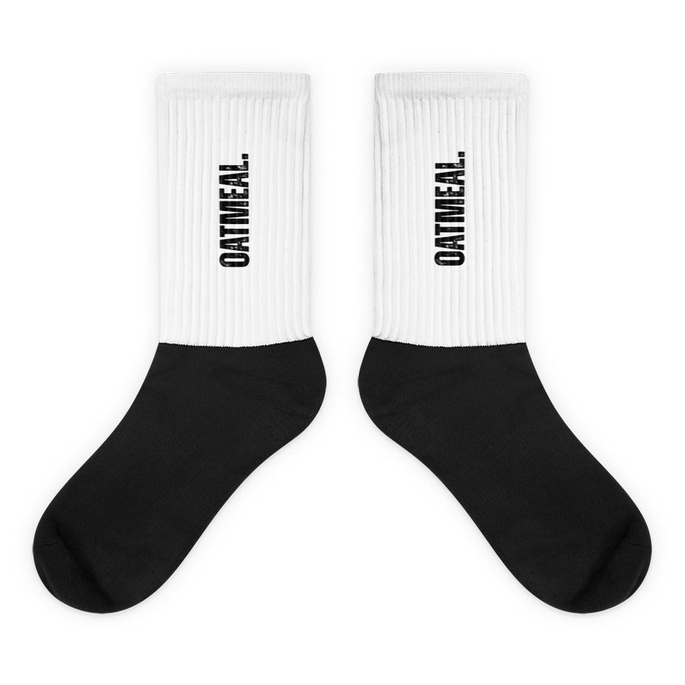 White socks with black soles and 'OATMEAL.' branding on a white background at Oatmeal Apparel Co.