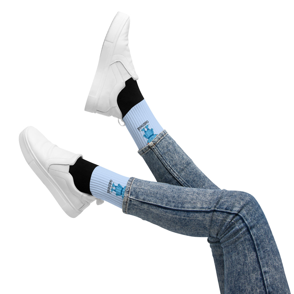 Person wearing light blue socks with black accents and white sneakers on a white background at Oatmeal Apparel Co.