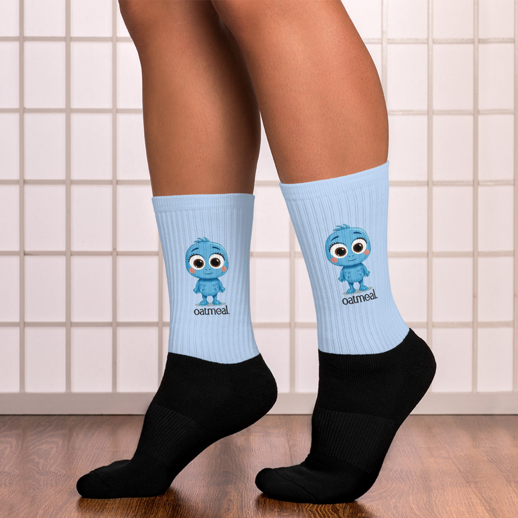 Person wearing light blue socks with Oatmeal cartoon character design and black socks on a tiled floor at Oatmeal Apparel Co.