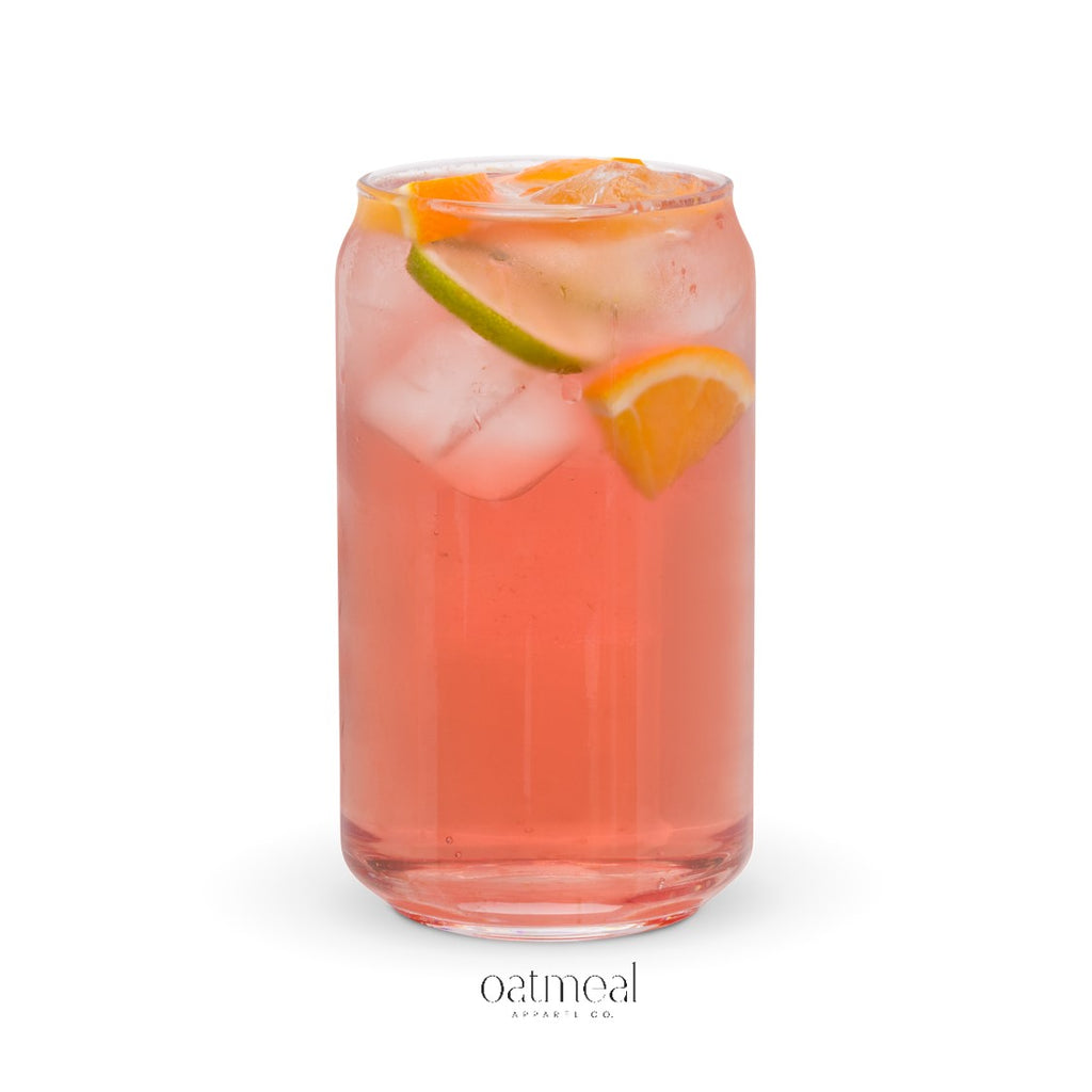 Glass of pink drink with ice and orange slices on a white background, featuring the brand 'oatmeal'.
