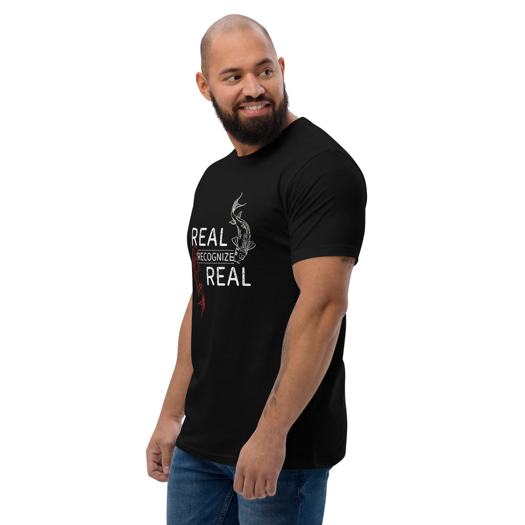 Man wearing a black t-shirt with 'REAL RECOGNIZE REAL' text and graphic design at Oatmeal Apparel Co.