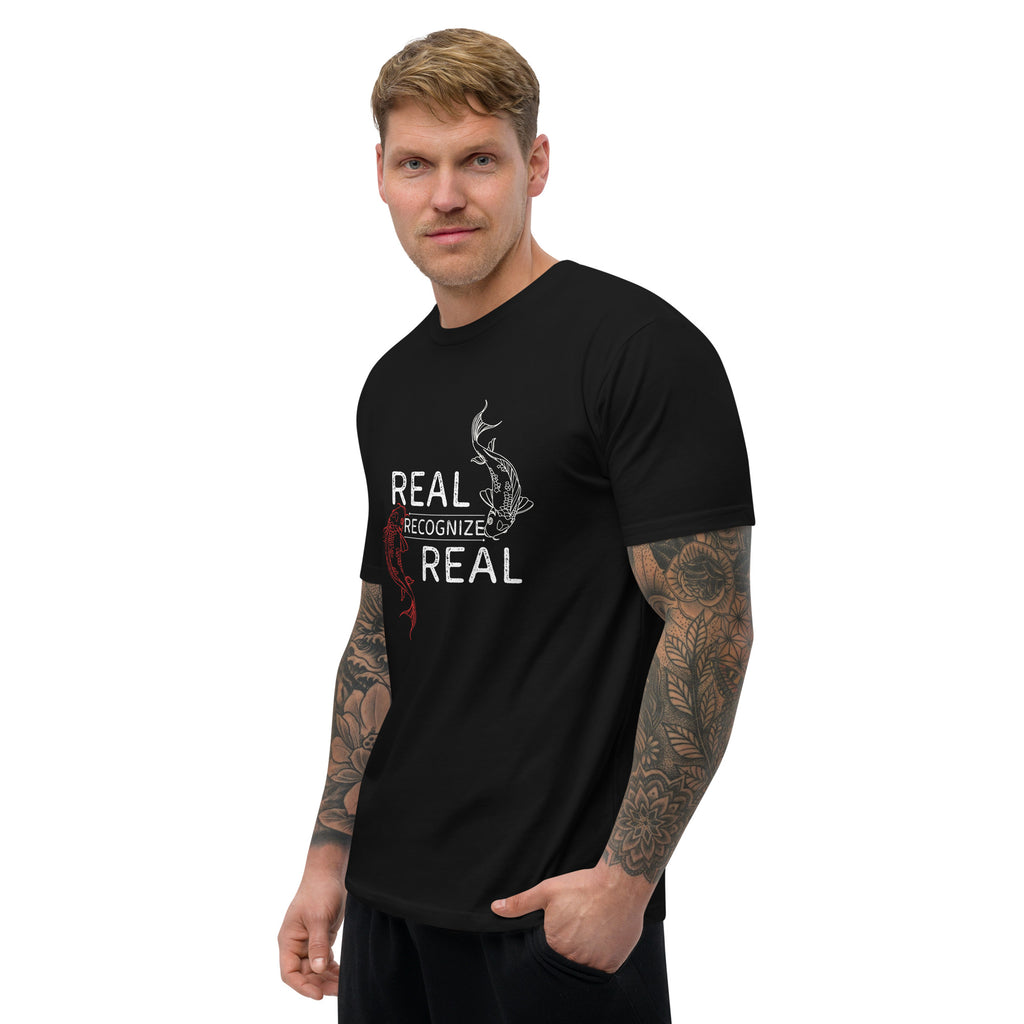 Man wearing a black t-shirt with 'REAL RECOGNIZE REAL' text and graphic at Oatmeal Apparel Co.