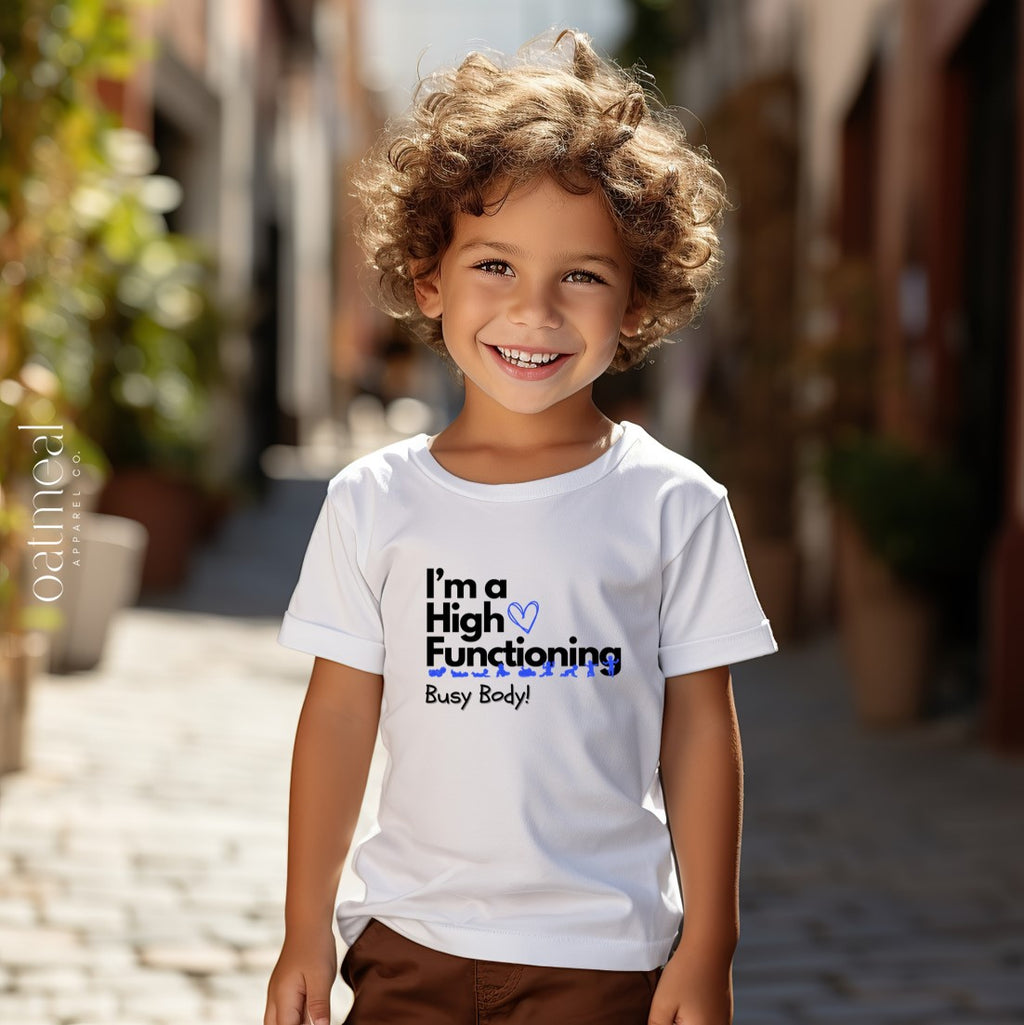 Child wearing a white t-shirt with 'High Functioning Busy Body' text standing on a street, shirt available at Oatmeal Apparel Co.
