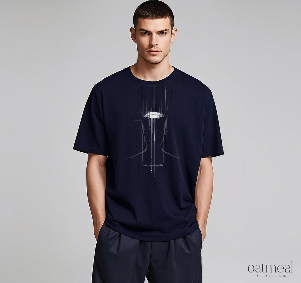 Man wearing a navy blue t-shirt with an unapologetic graphic design on a plain background, featuring the brand 'Oatmeal Apparel Co'.