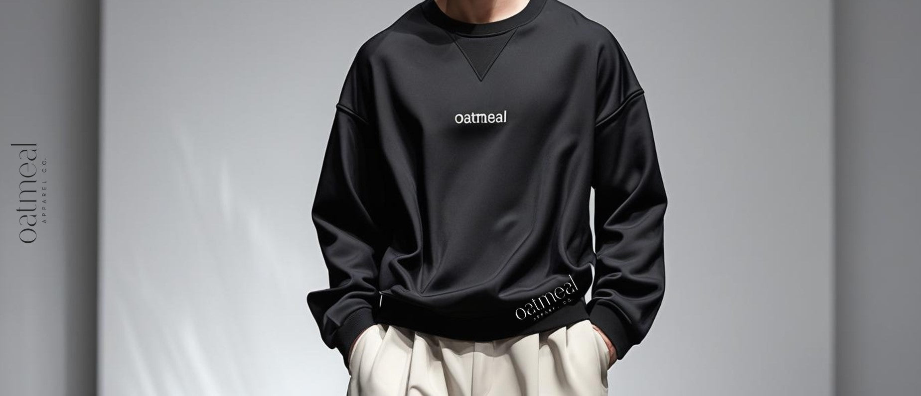 Man wearing a black sweatshirt with 'oatmeal' branding on a gray background at Oatmeal Apparel Co., premium organic cotton collection.