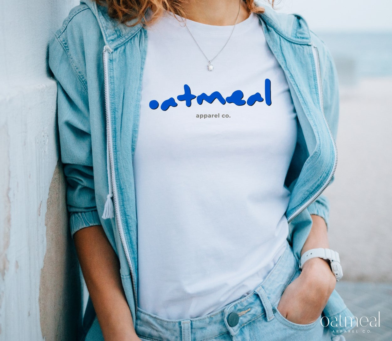 Person wearing a white t-shirt with 'oatmeal apparel co.' branding, standing against a light background.