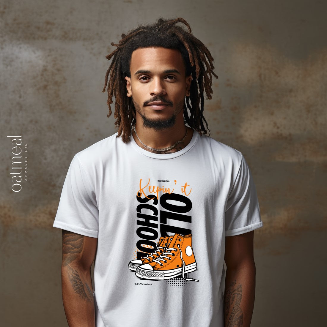 Man wearing a white t-shirt with a graphic design on a textured brown background at Oatmeal Apparel Co.