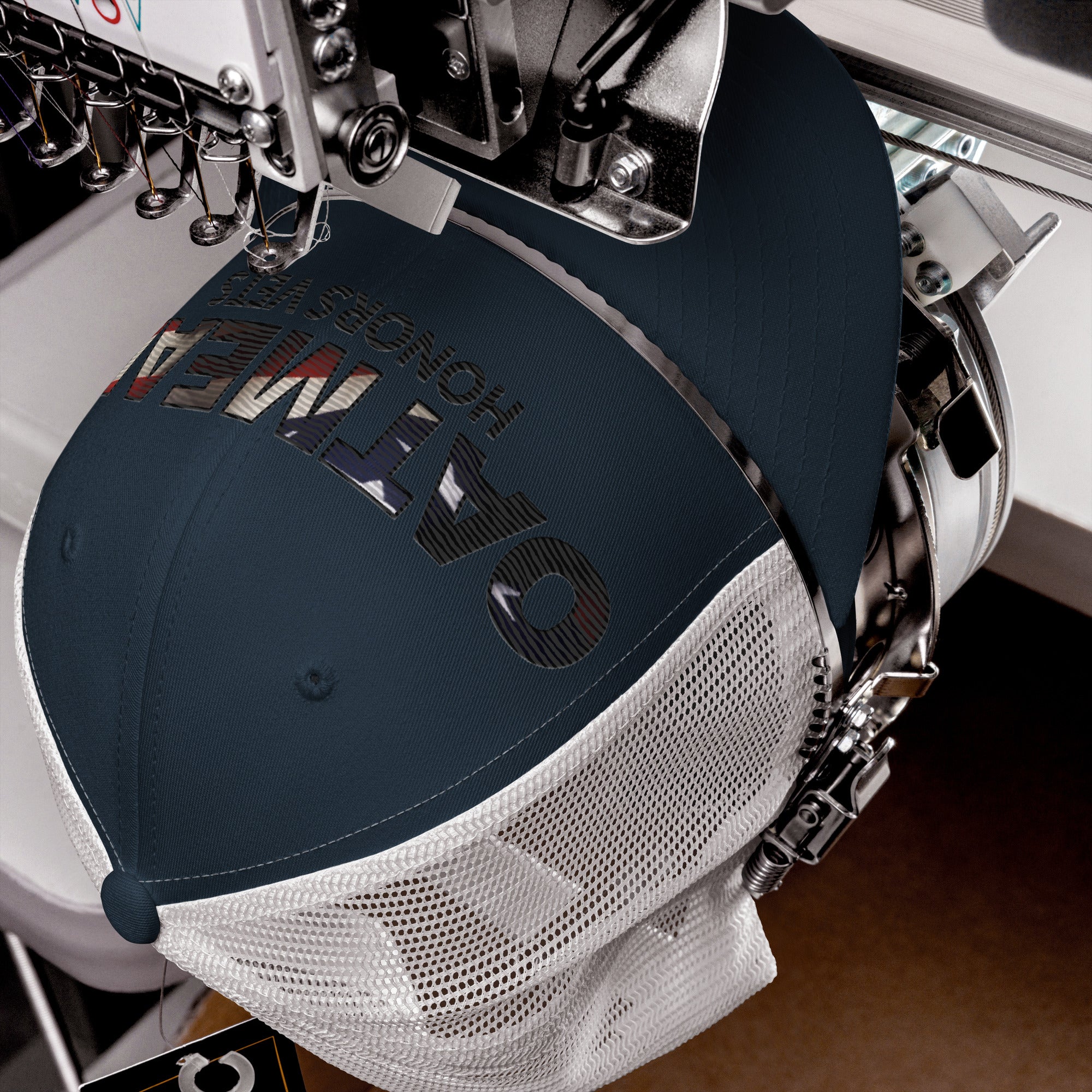 Embroidery machine with a cap being embroidered on a wooden surface at Oatmeal Apparel Co.