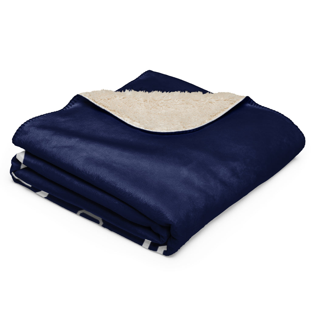 Folded navy blue blanket with white sherpa lining on a white background at Oatmeal Apparel Co.