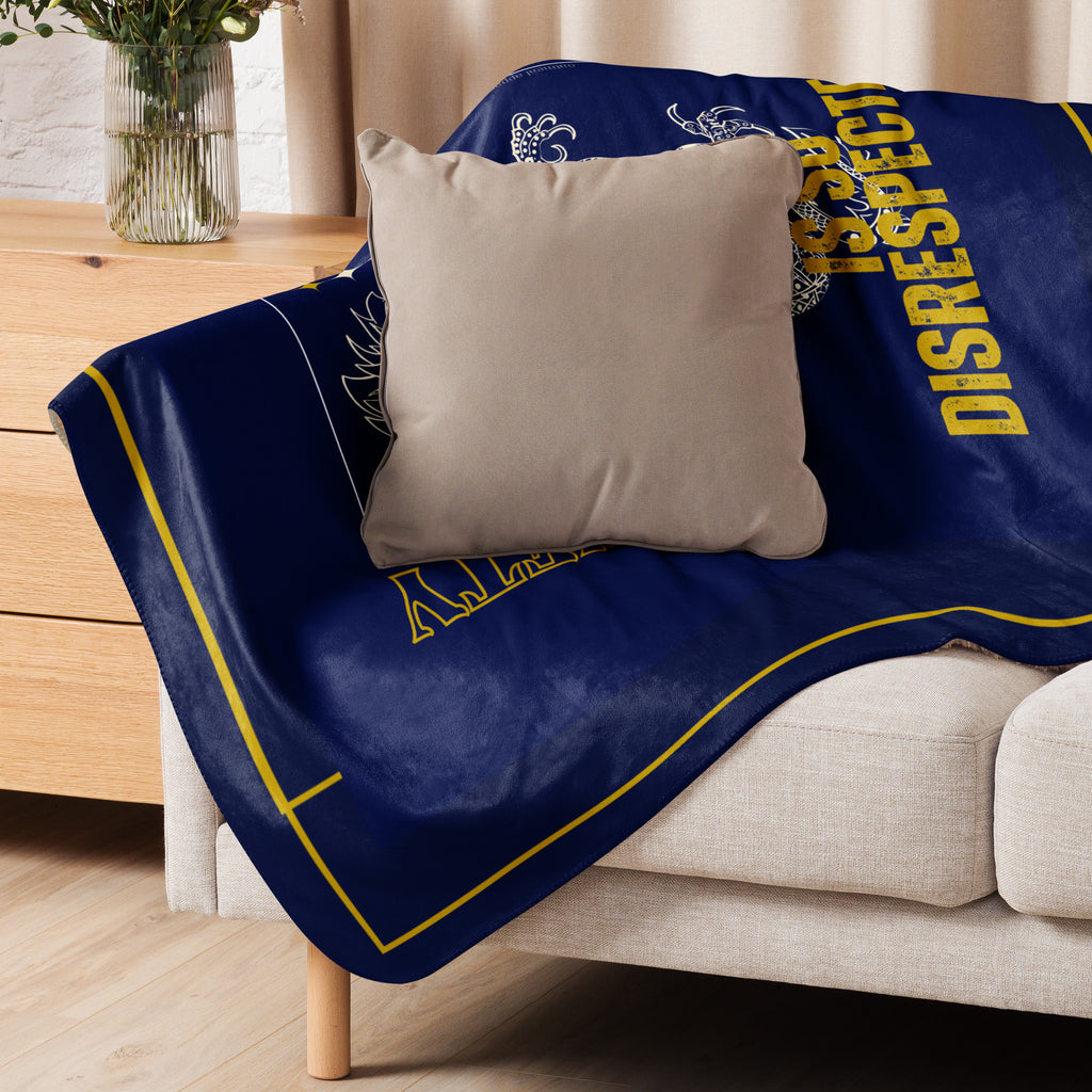 Navy plush blanket with yellow text draped over a couch with a beige pillow at Oatmeal Apparel Co.