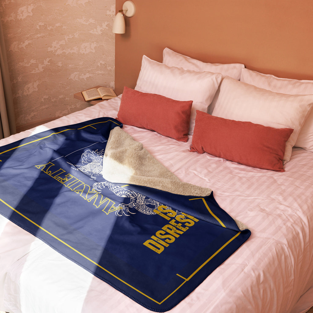 Blue blanket with yellow text on a bed with red and white pillows at Oatmeal Apparel Co.