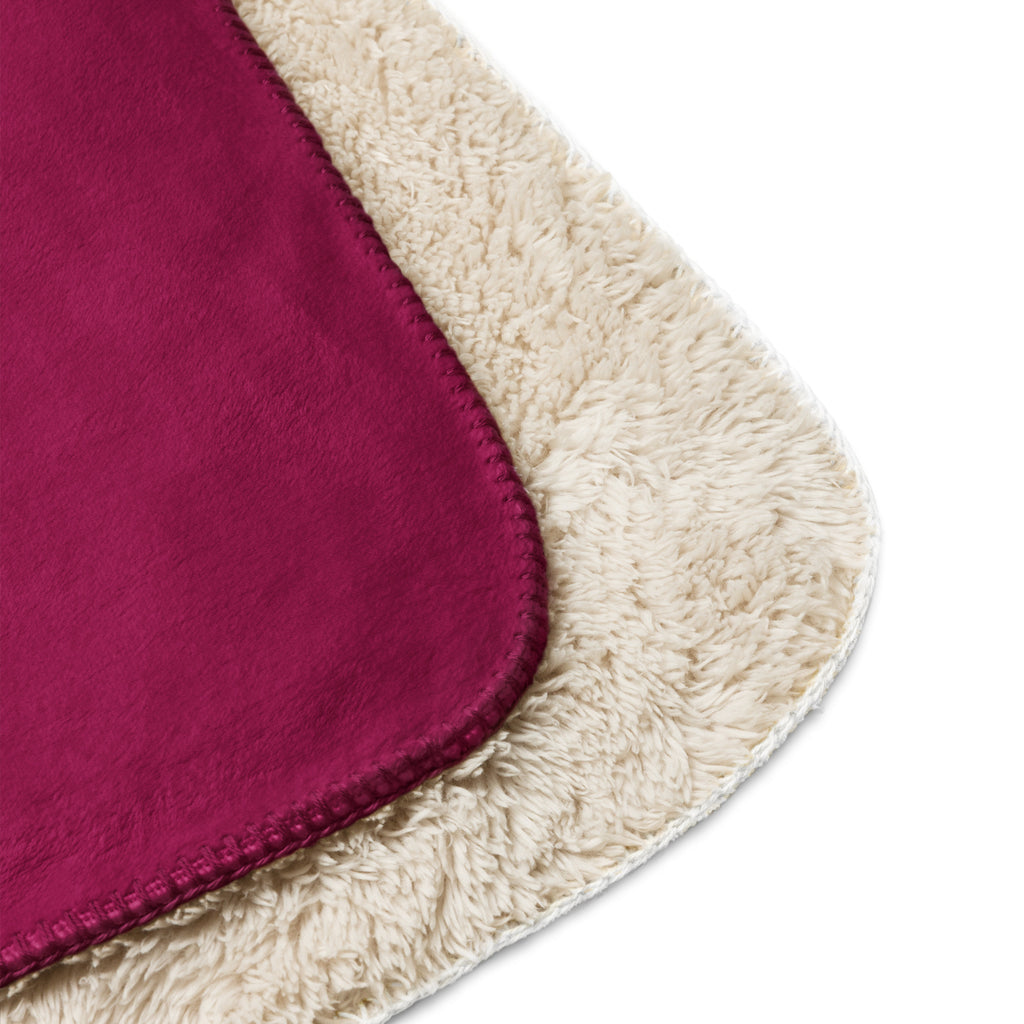 Close-up of a sherpa blanket with a maroon fabric and beige border at Oatmeal Apparel Co.