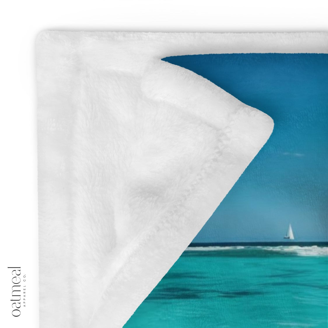 Blanket with one showing a sailboat on a blue ocean and the other a white background at Oatmeal Apparel Co.