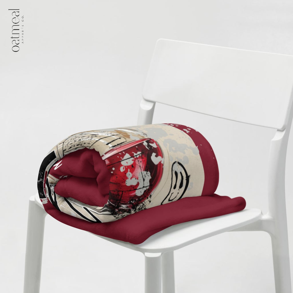 Folded blanket with a red and beige pattern on a white chair at Oatmeal Apparel Co.