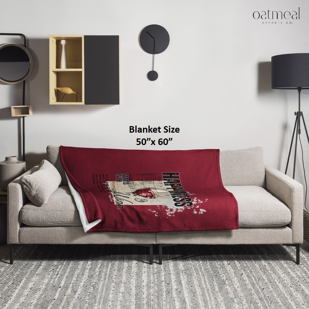 Red blanket with graphic design draped over a gray sofa in a modern living room setting at Oatmeal Apparel Co.