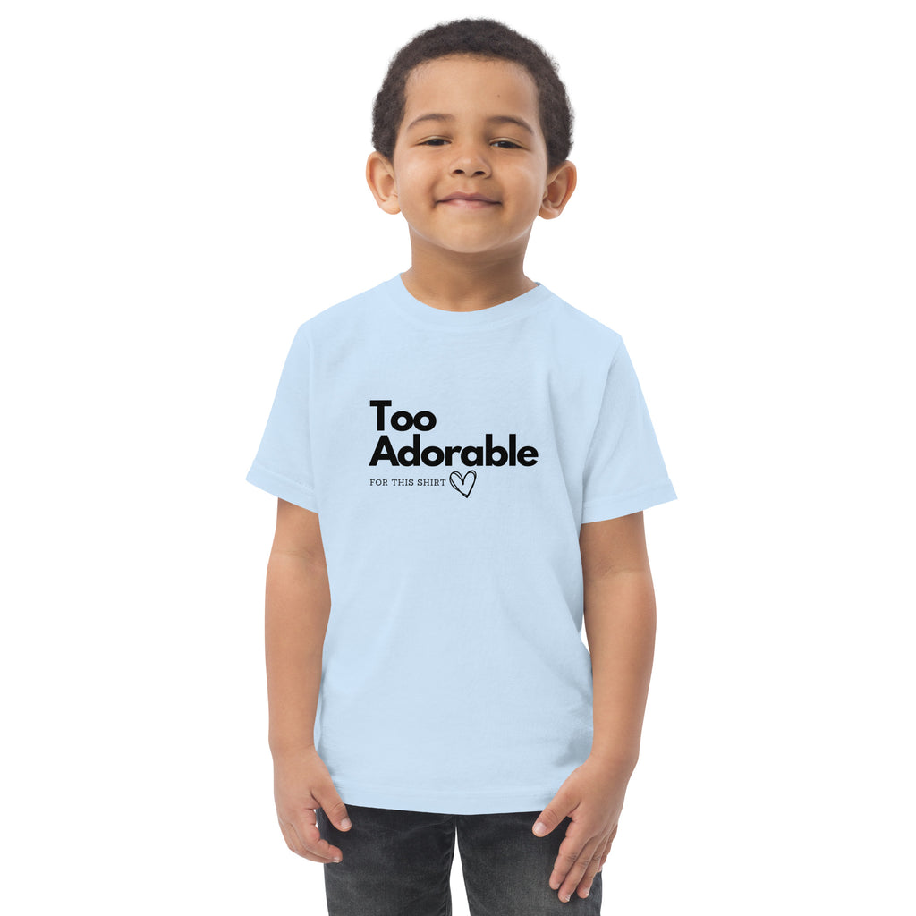 Child wearing a light blue t-shirt with 'Too Adorable for This Shirt' text on a white background at Oatmeal Apparel Co.