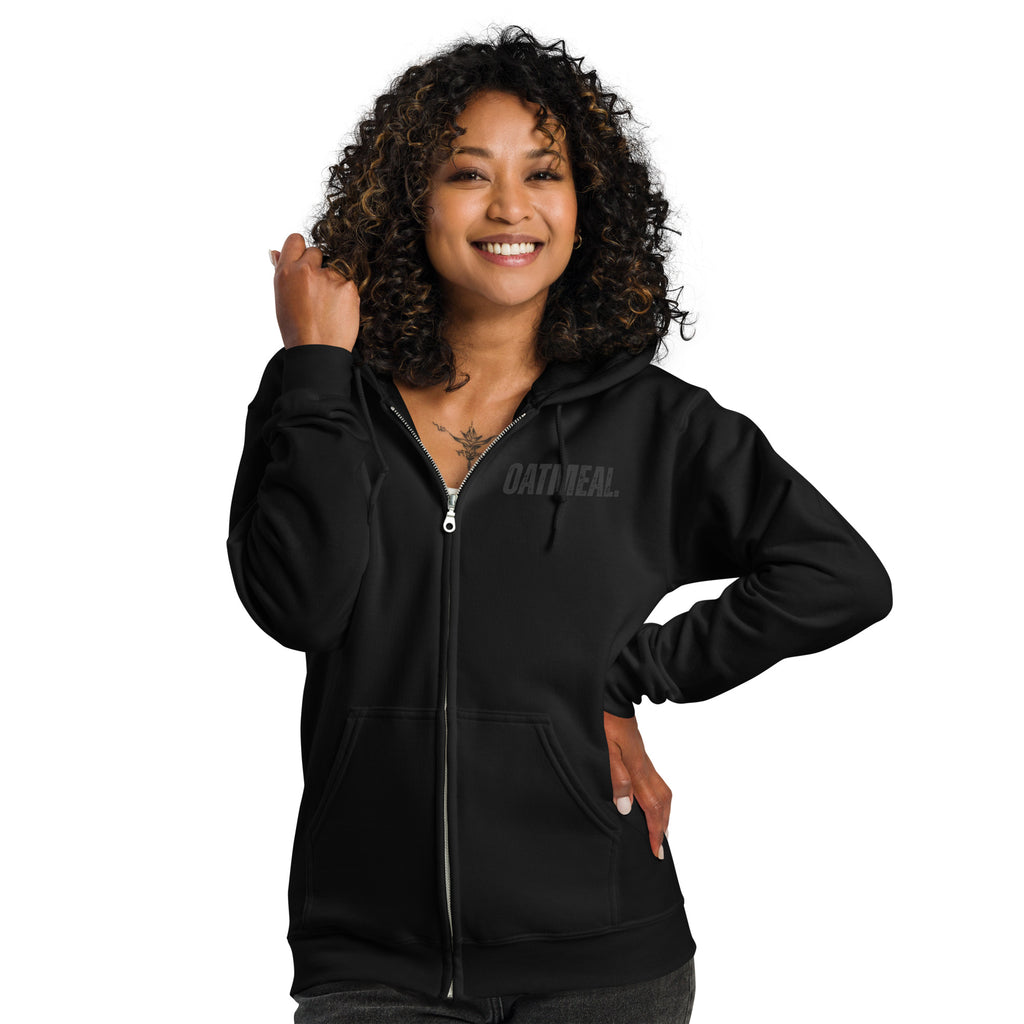 Woman wearing a black hoodie with a 'OATMEAL' brand logo on a white background at Oatmeal Apparel Co.