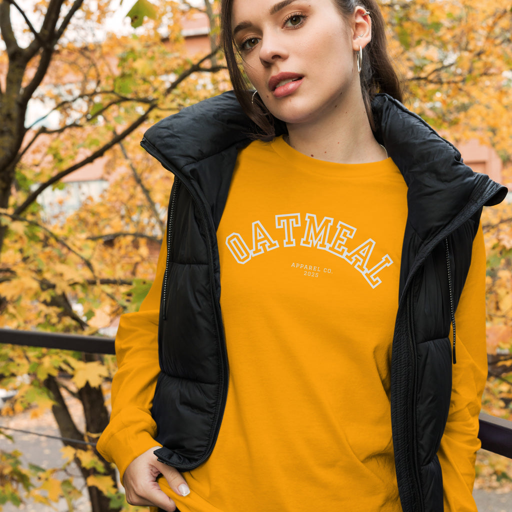 Woman wearing a yellow 'OATMEAL' long-sleeve with a black jacket in an autumn setting at Oatmeal Apparel Co., Sports Edition Design.