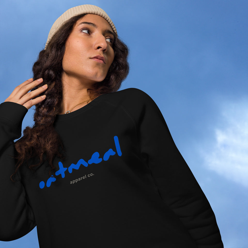 Person wearing a black sweatshirt with blue 'oatmeal' branding against a blue sky at Oatmeal Apparel Co.