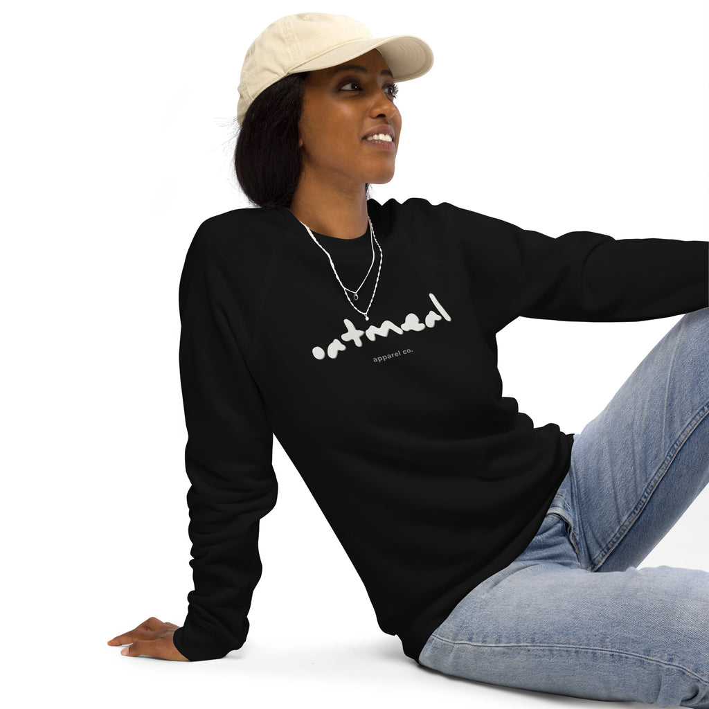 Person wearing a black long-sleeve shirt with 'oatmeal apparel co.', sitting on a white background