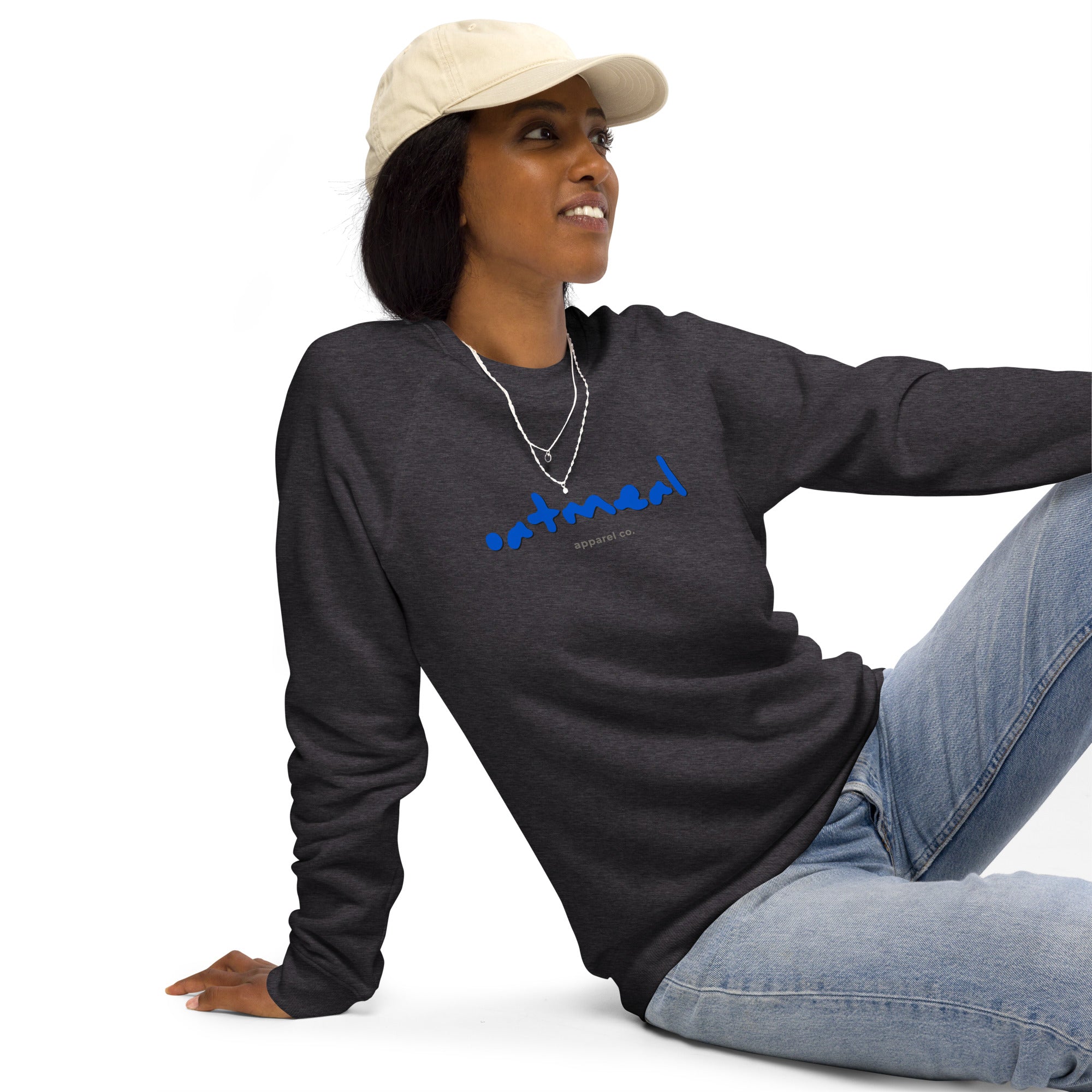 Woman wearing a dark long-sleeve shirt with blue 'oatmeal' branding and light blue jeans on a white background at Oatmeal Apparel Co.