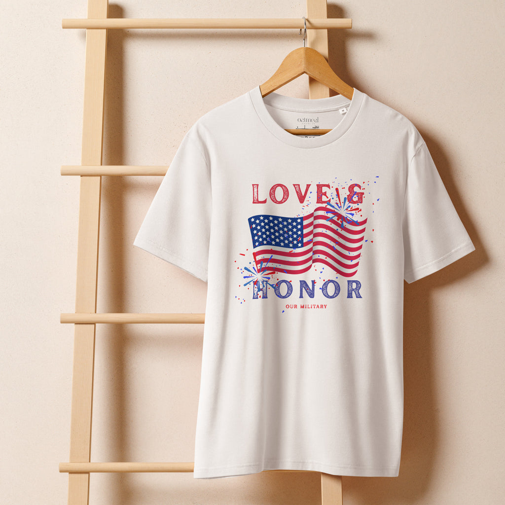 White t-shirt hanging on a rack with 'Love & Honor Our Military' text and US flag design, avail exclusively at Oatmeal Apparel Co.