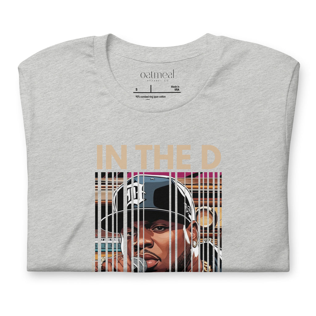 Folded Gray t-shirt with a custom graphic of hip-hop person wearing a cap and text 'IN THE D' on a white background at Oatmeal Apparel Co.