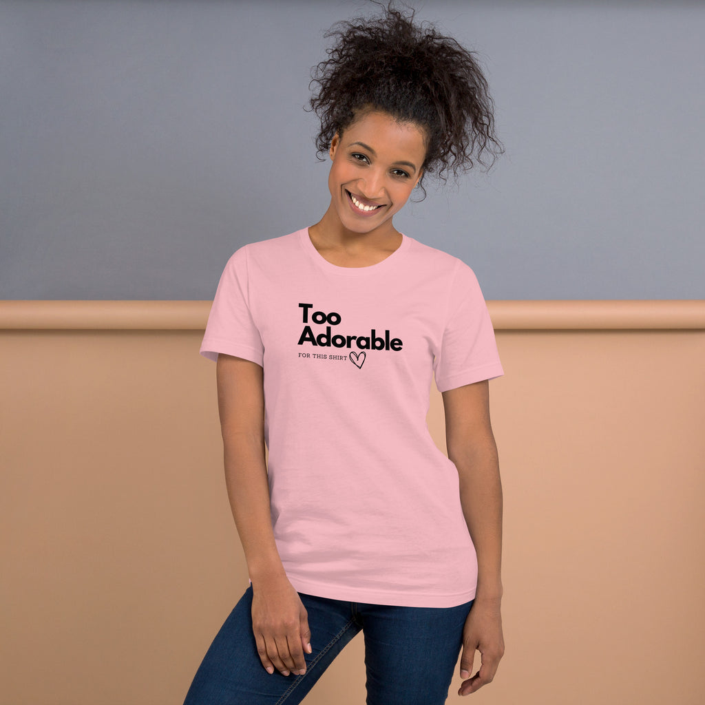Woman wearing a pink t-shirt with 'Too Adorable' text, standing against a plain background available at Oatmeal Apparel Co.