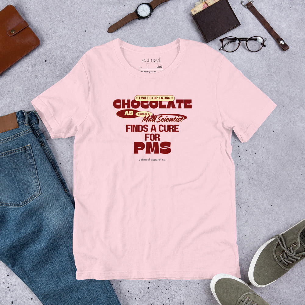 Pink t-shirt with humorous text design on a gray surface with jeans, shoes, and accessories available at Oatmeal Apparel Co.