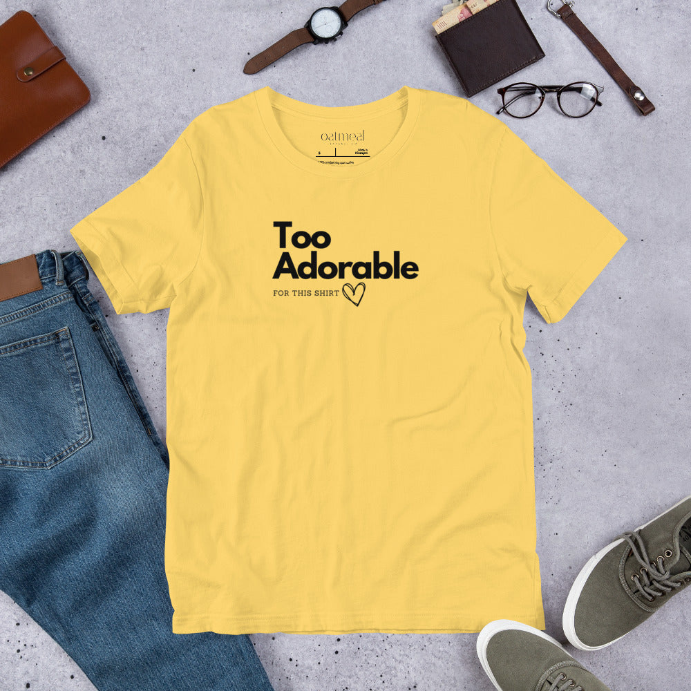 Yellow t-shirt with 'Too Adorable' text on a gray surface with jeans, shoes, and accessories available at Oatmeal Apparel Co.