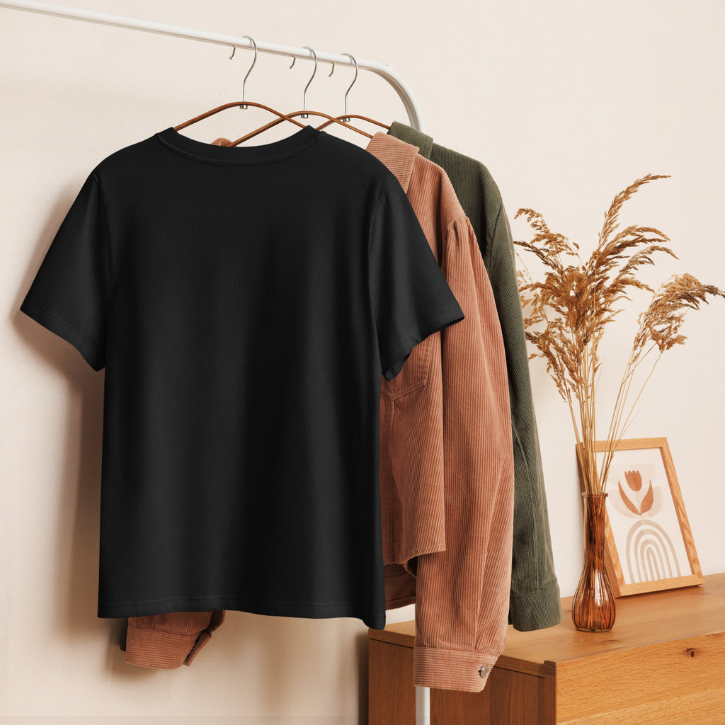 Black t-shirt on a hanger with other clothing items in the background showing off the clean polished look of the Women's Organic Tee at Oatmeal Apparel Co.