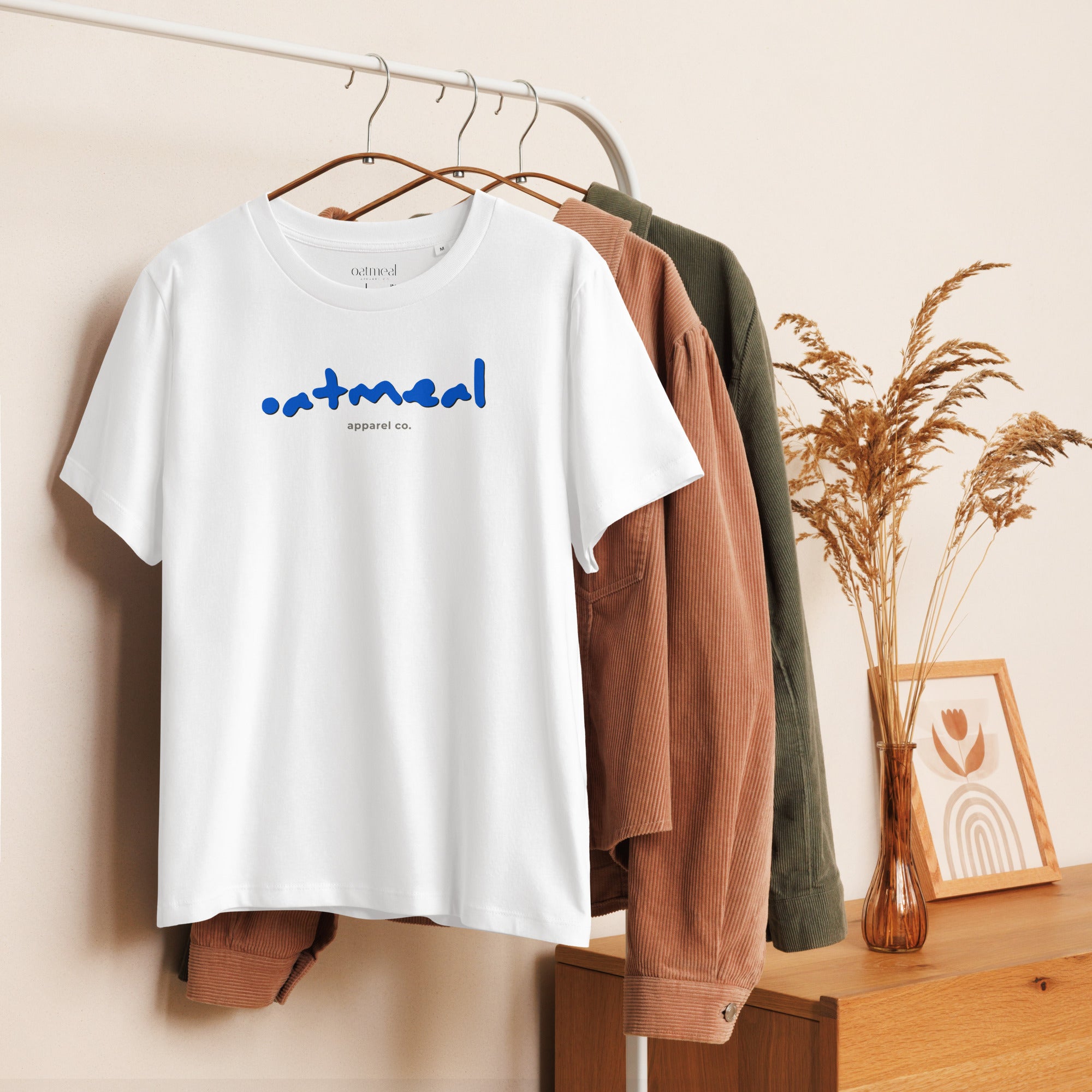 White t-shirt with 'oatmeal' branding on a hanger against a neutral background at Oatmeal Apparel Co.
